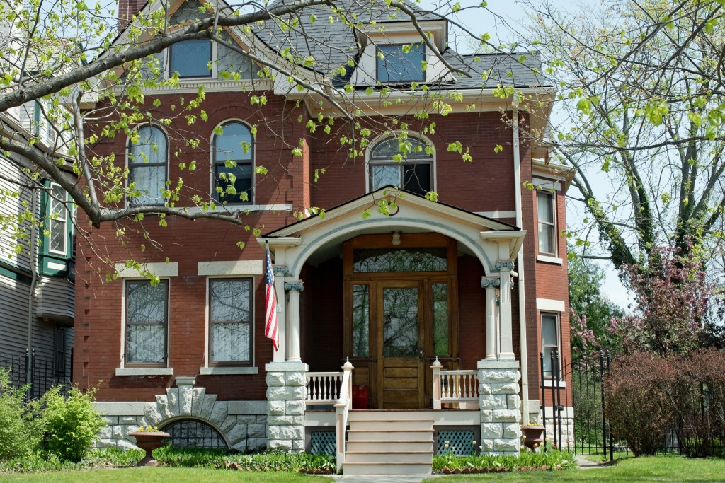 Large red brick home with American flag and green grass