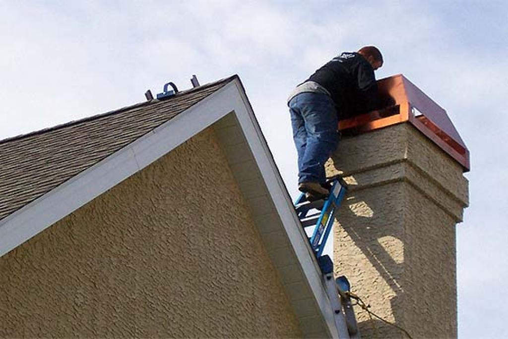 Man replacing chimney cap on house