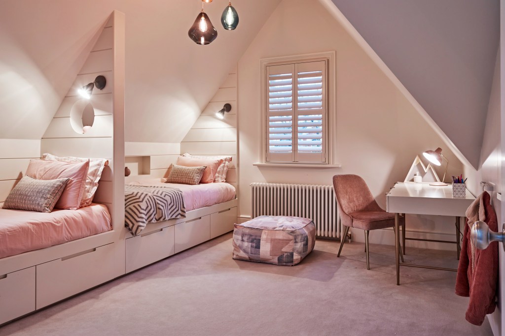 Pink attic bedroom with pendant lights, two day beds, desk