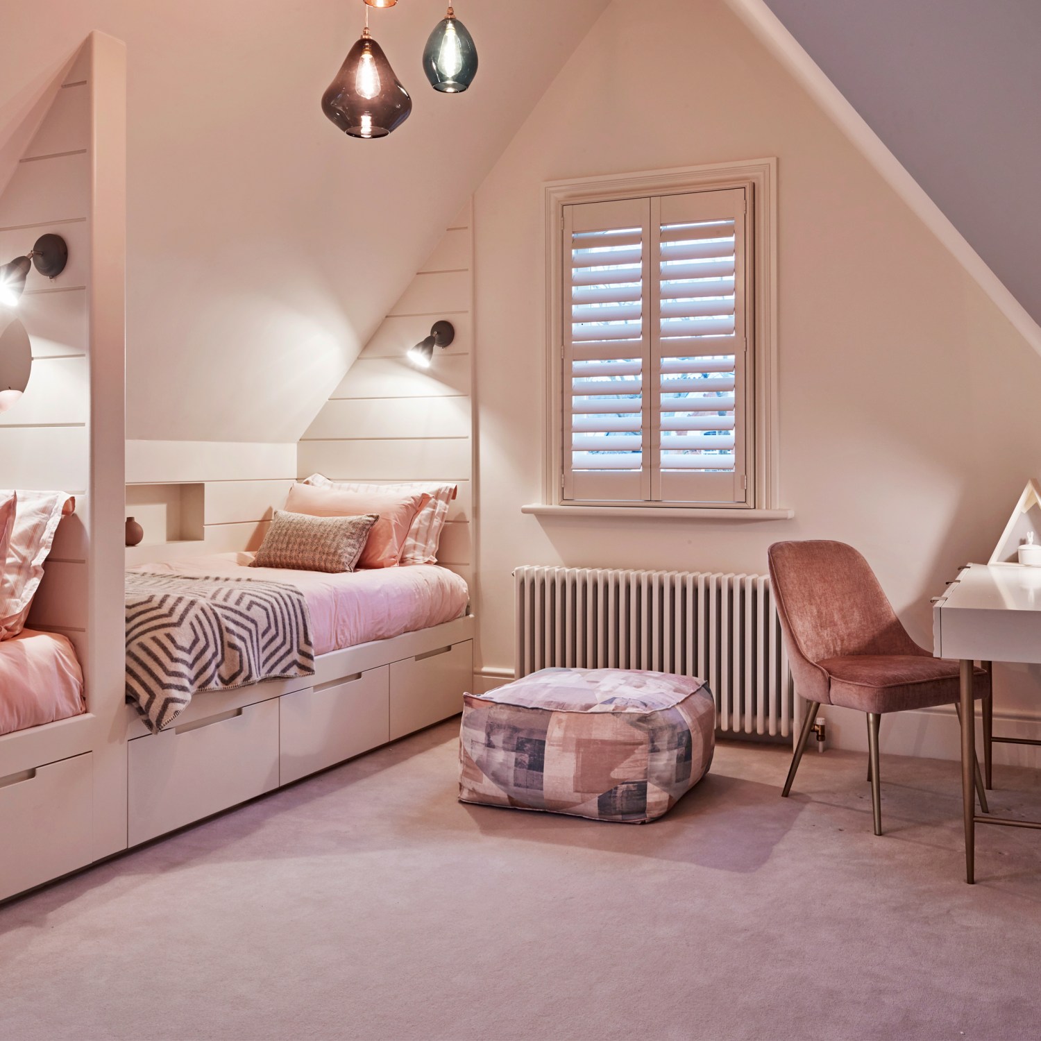 Pink attic bedroom with pendant lights, two day beds, desk