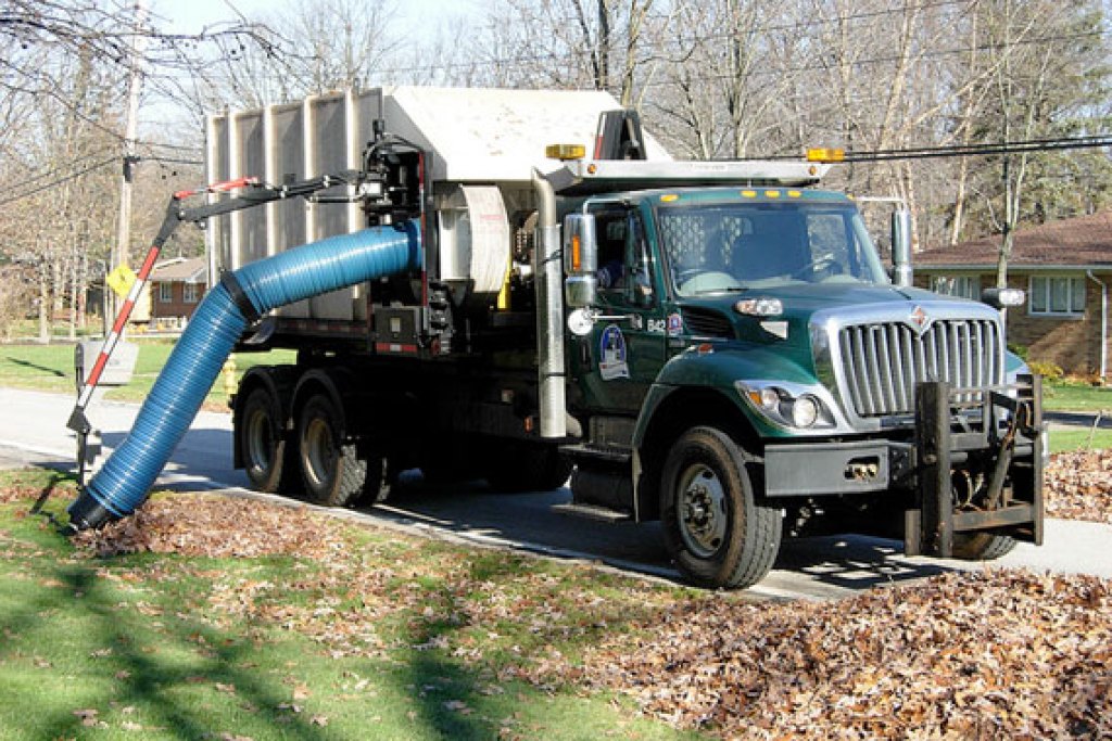 A truck vacuuming leaves on a residential street