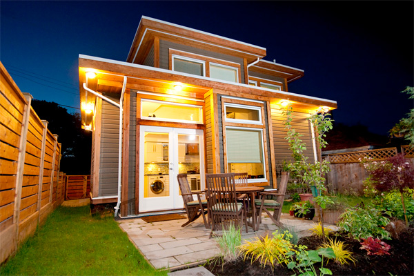 Night on back patio of tiny home with furniture and garden