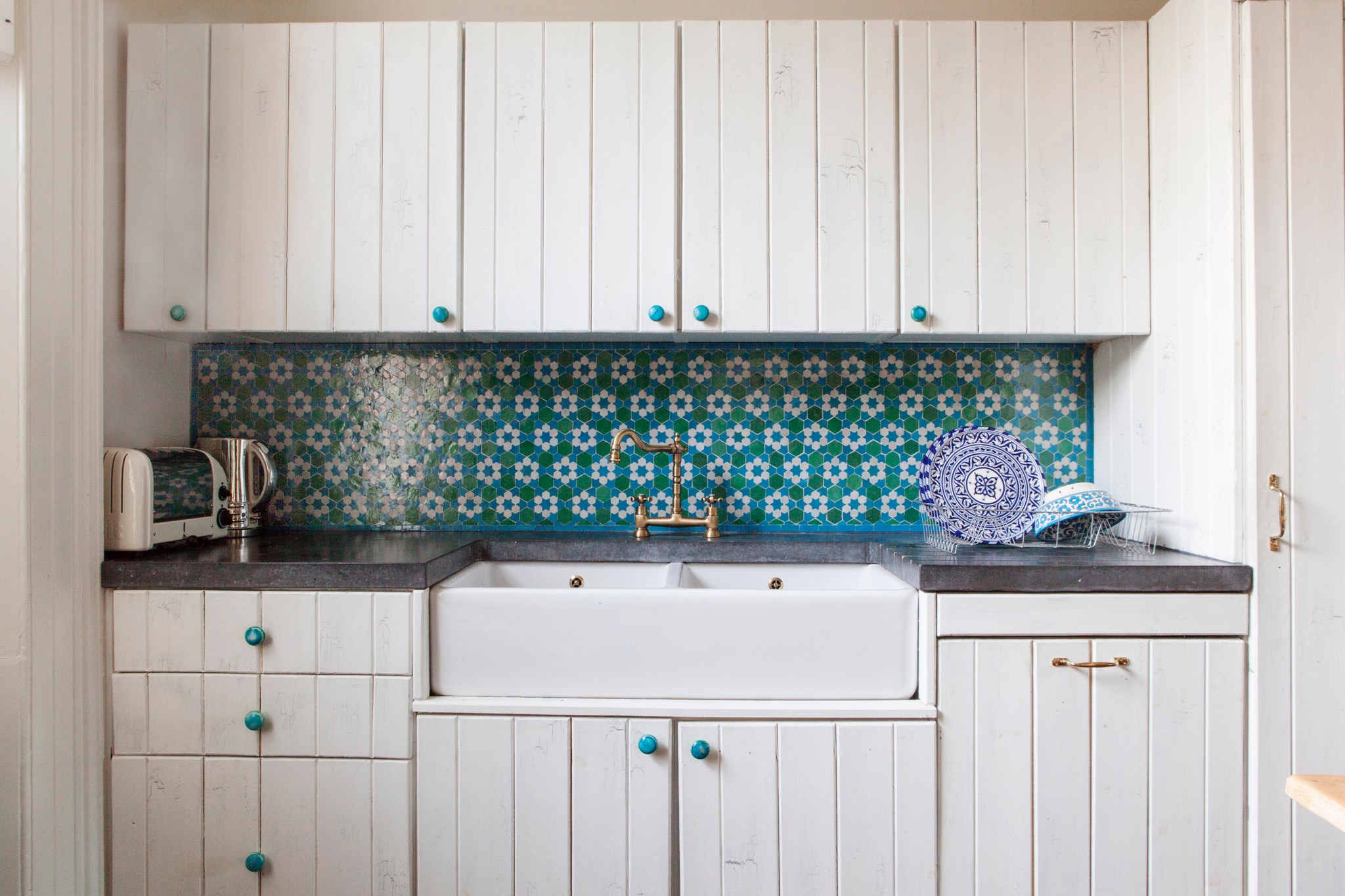 Teal knobs on white cabinets in an eclectic kitchen