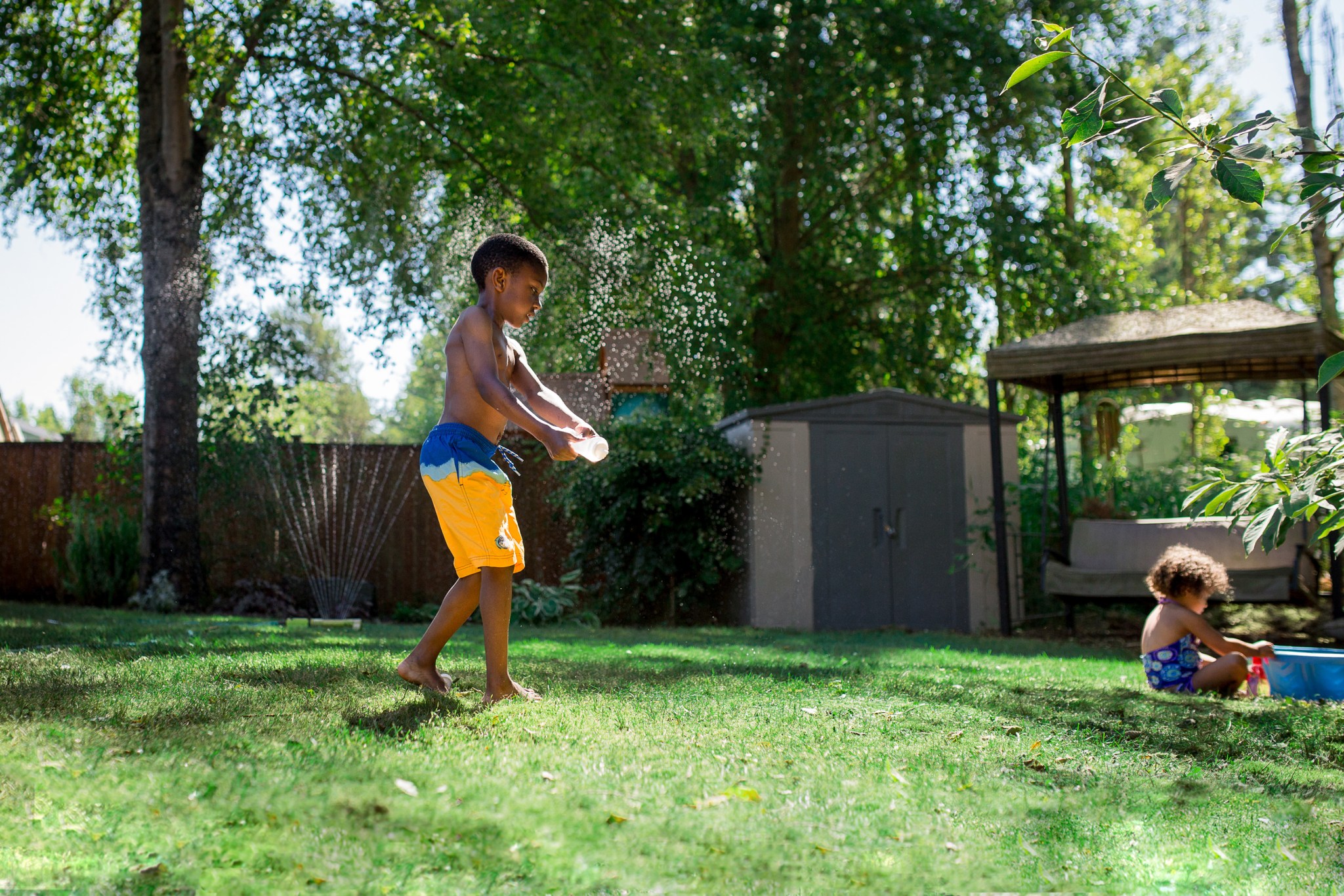 Boy playing a back yard sprinkler in summer