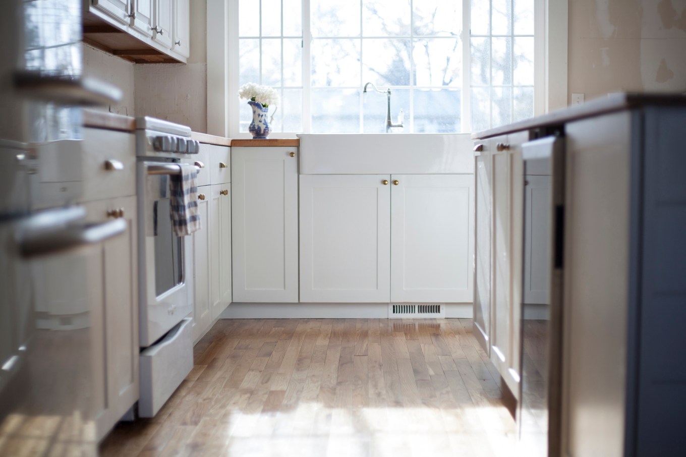 Low view of white kitchen sink and cabinets beneath window