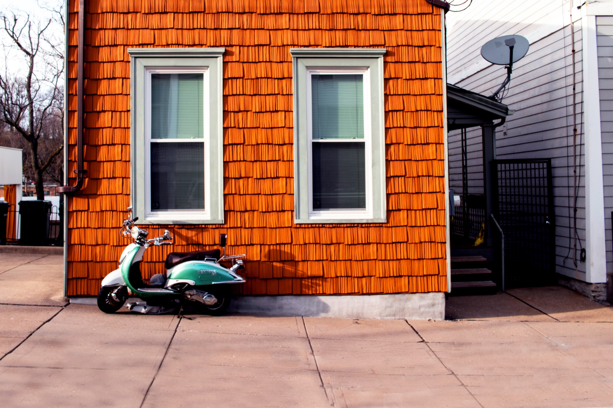 Wood-paneled house with green scooter resting against it