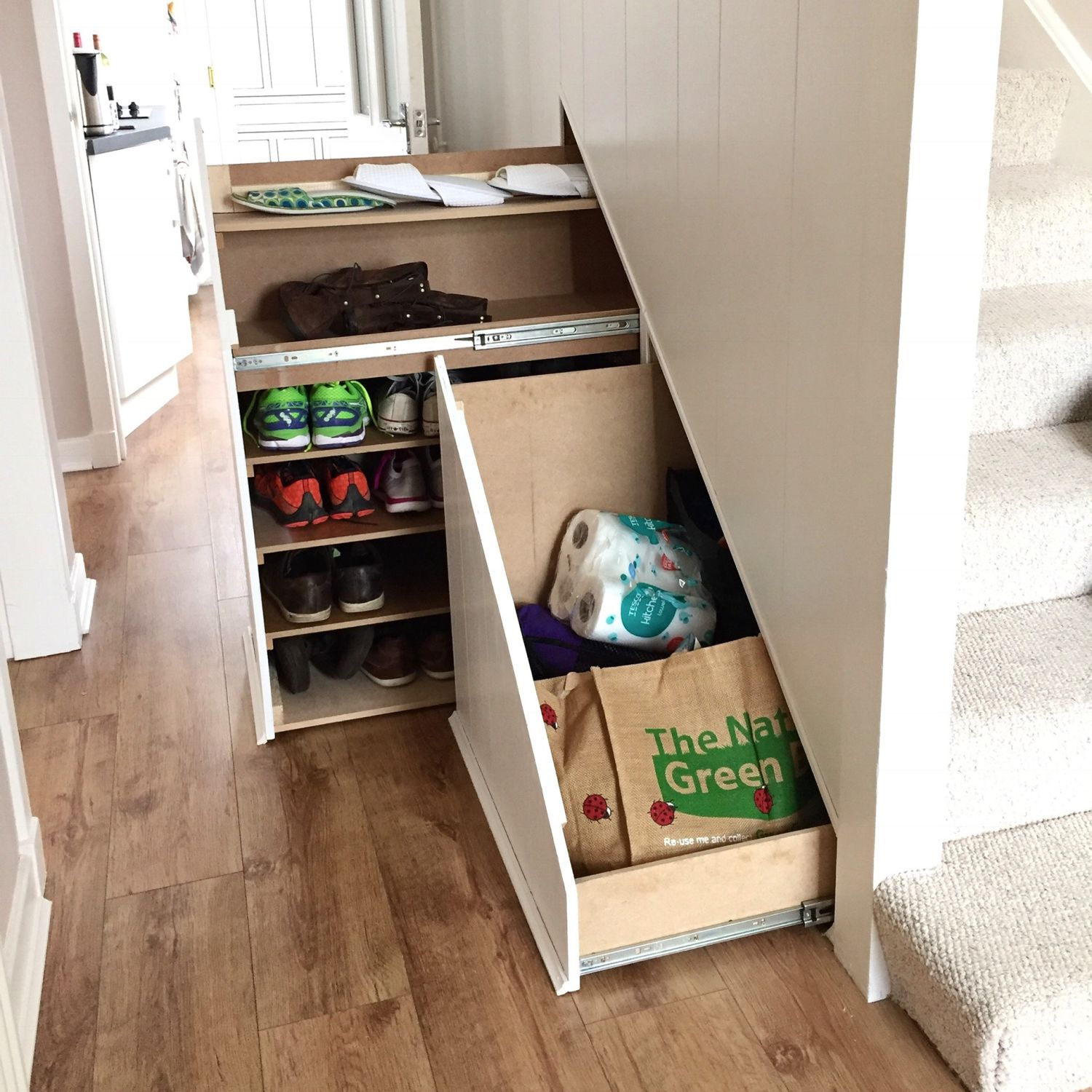 Drawers beneath stairs pull out to reveal bags and shoes