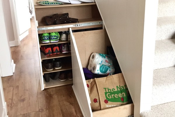 Drawers beneath stairs pull out to reveal bags and shoes