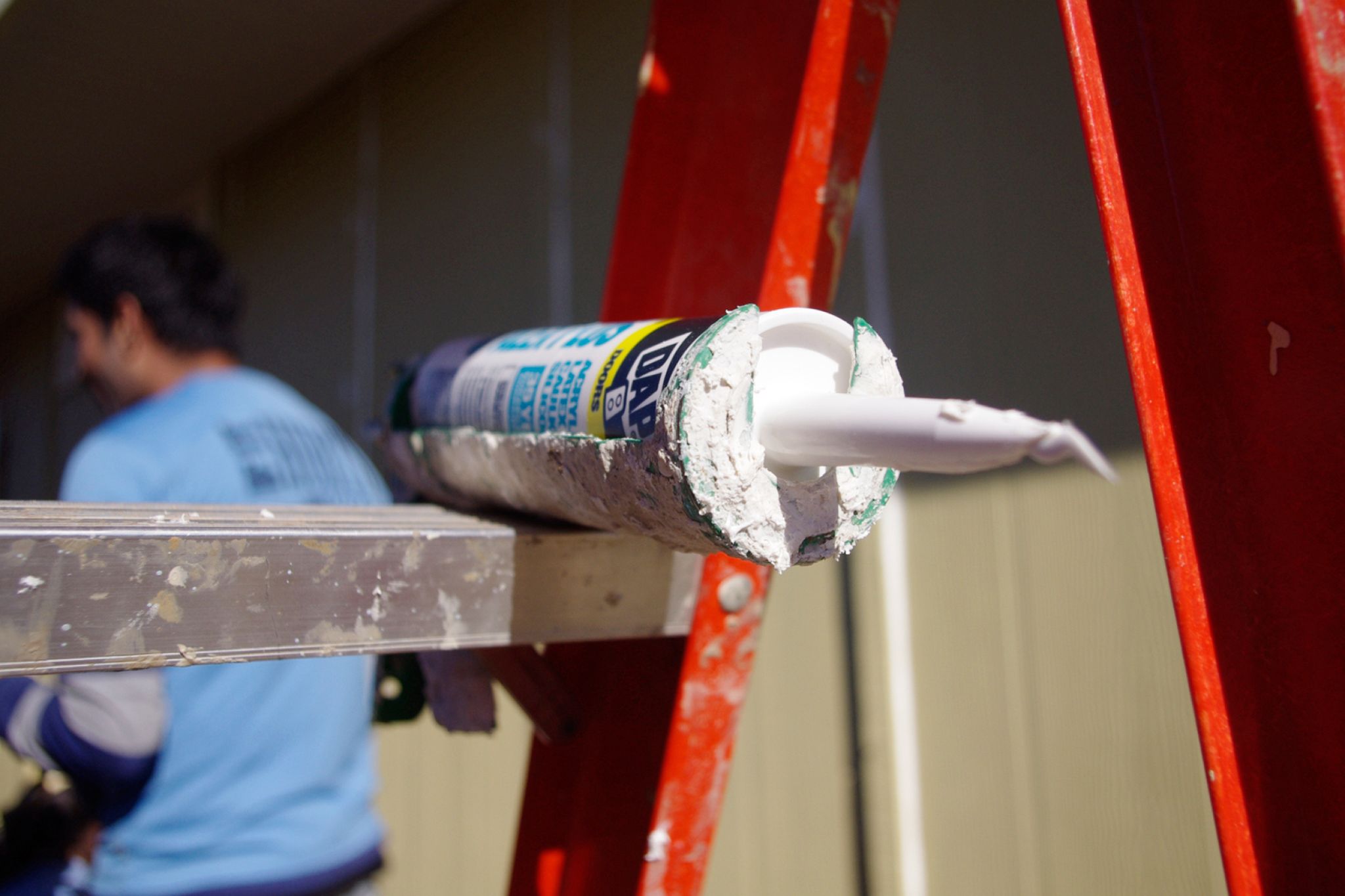 Tube of caulk resting on a ladder