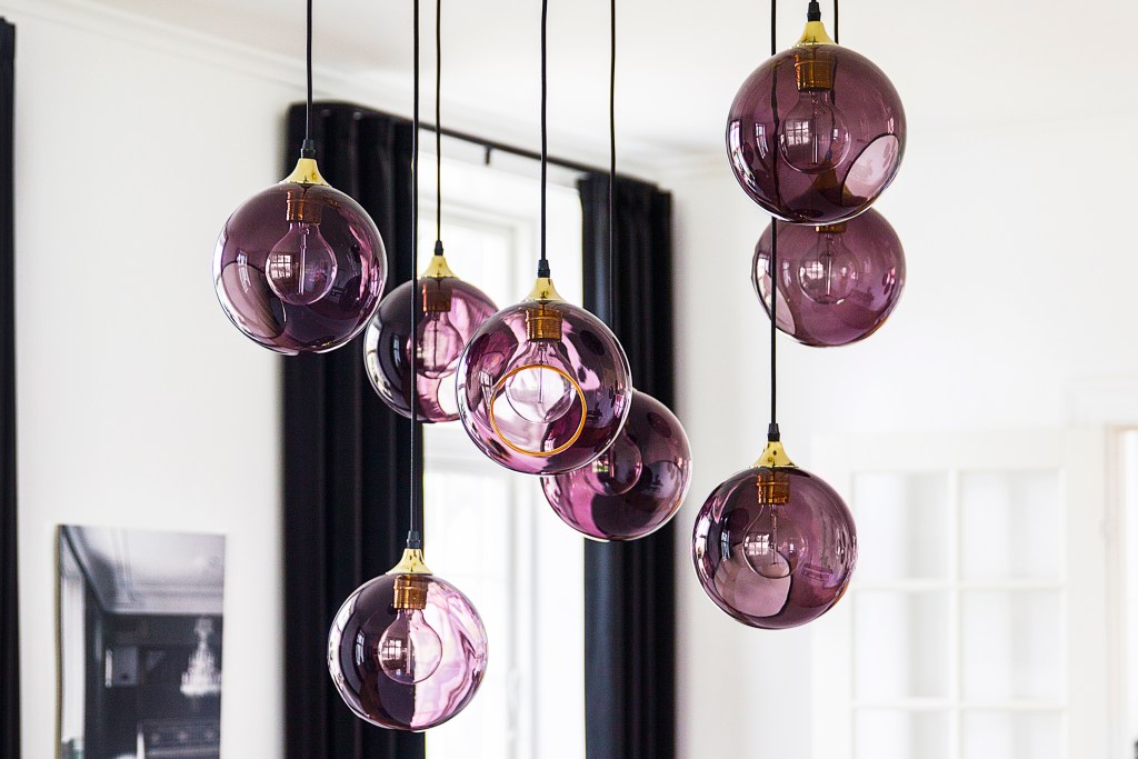 Cluster of purple globe lights hanging in a white room