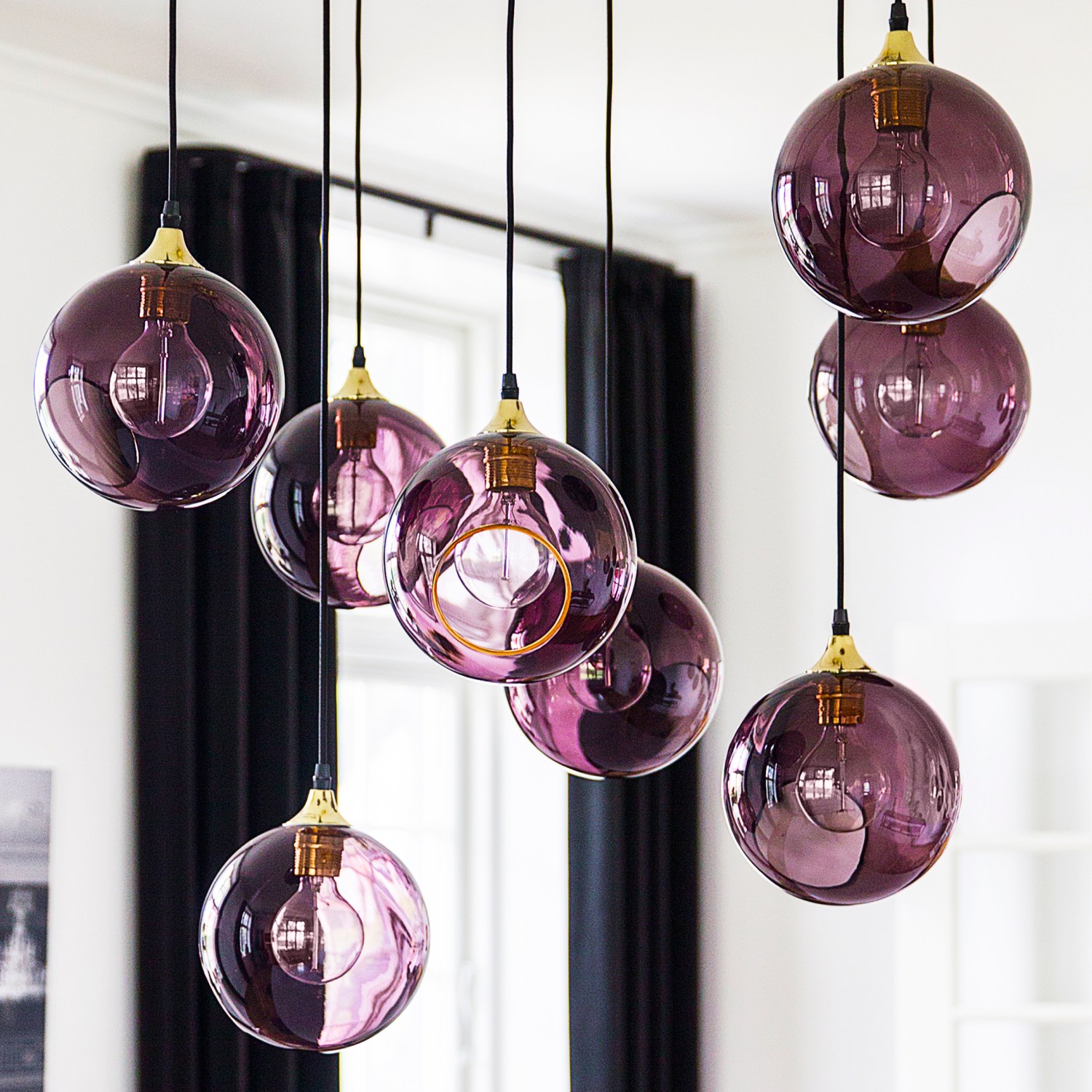 Cluster of purple globe lights hanging in a white room