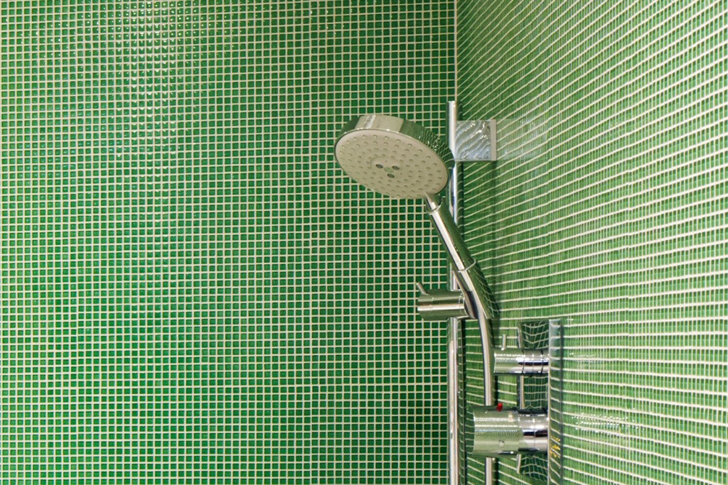 A modern bathroom with a green tile shower