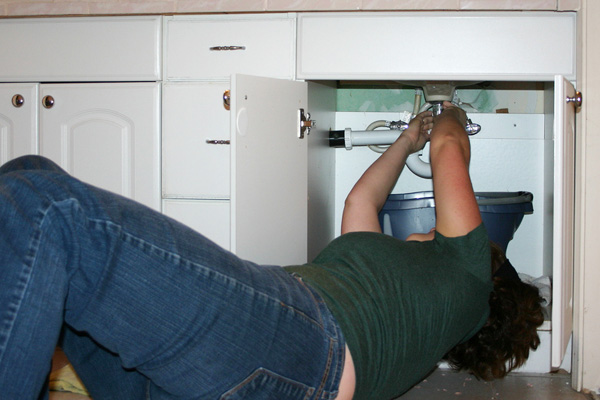 Woman fixing a leaking sink
