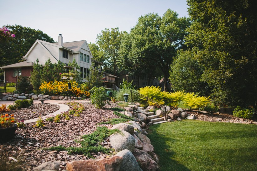 A front yard with pink and yellow flowers in a mulched bed