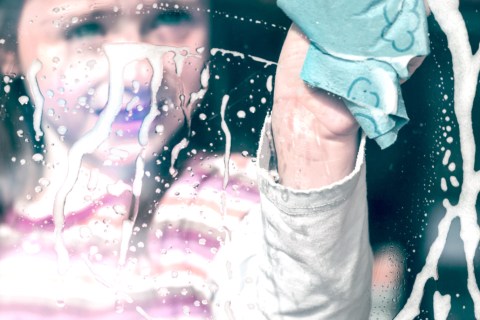 Girl cleaning a window at her home