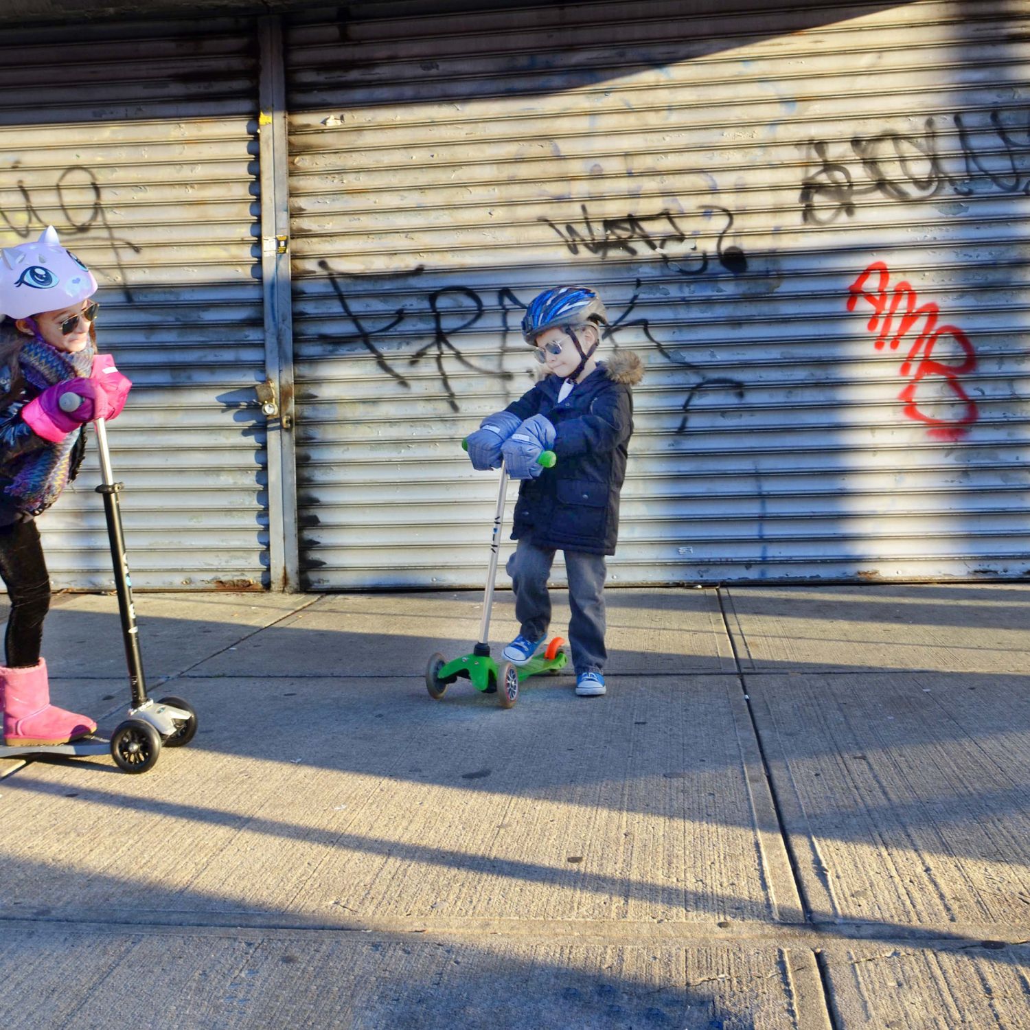 Kids riding their scooters on an urban sidewalk