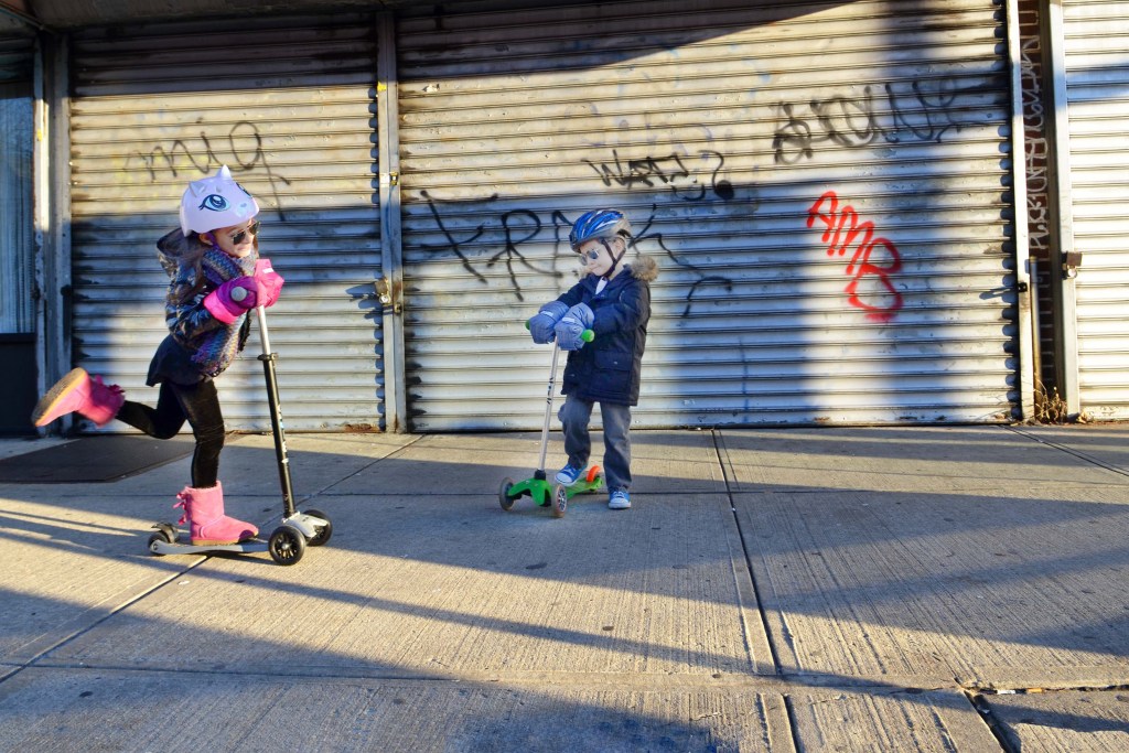 Kids riding their scooters on an urban sidewalk