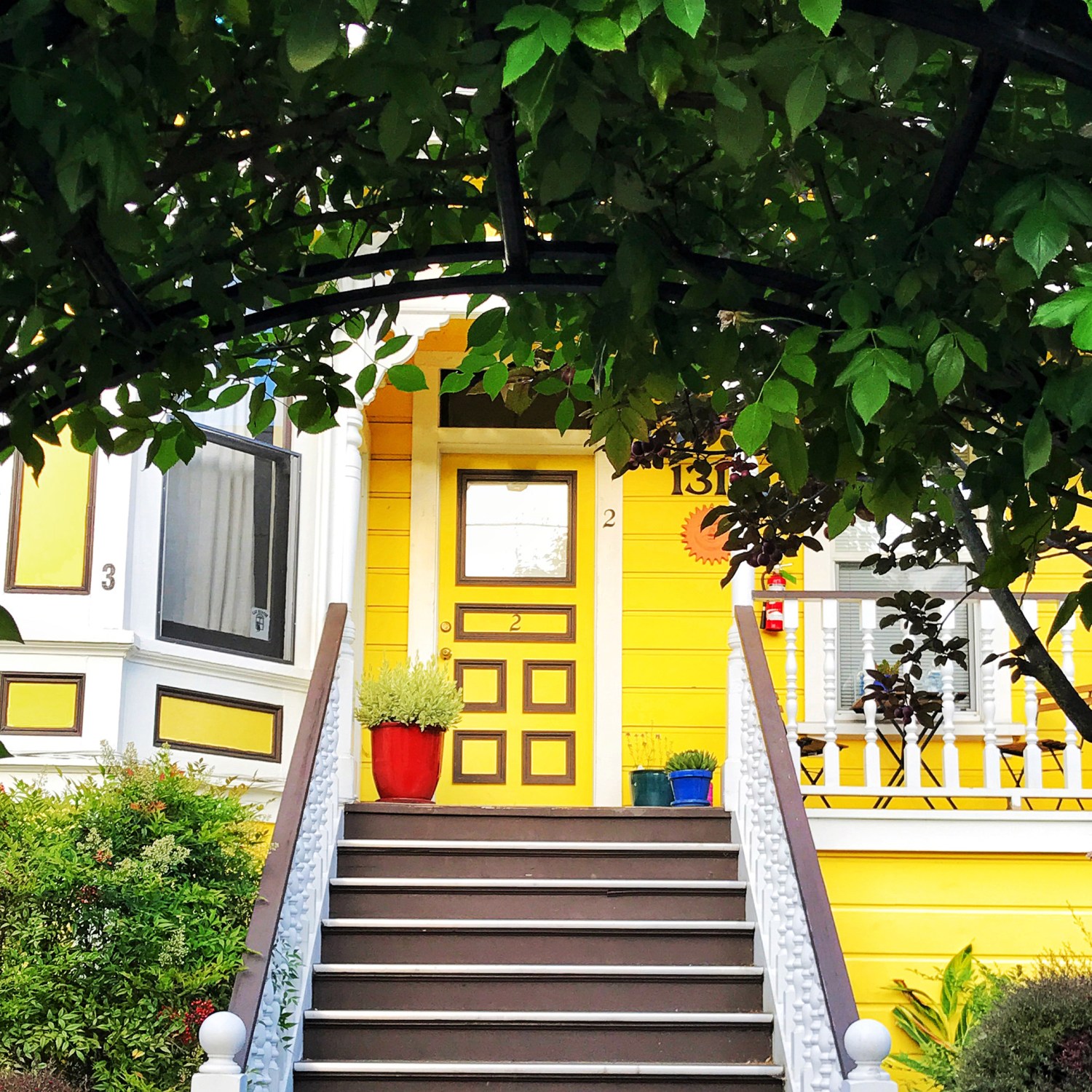Foliage archway framing front steps and yellow door