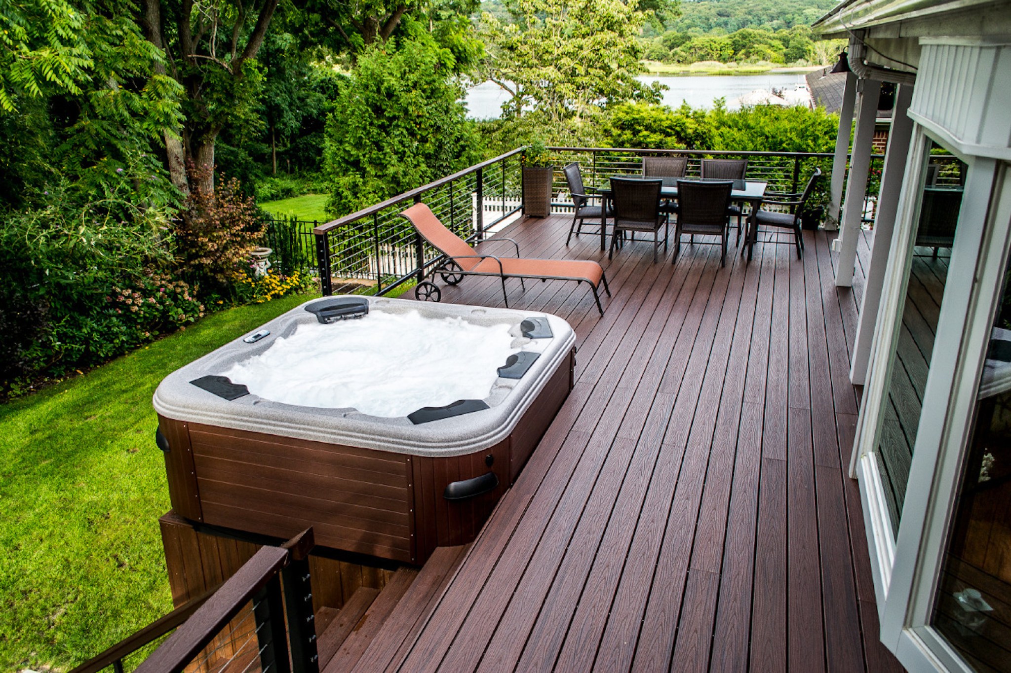 Wood deck with hot tub overlooking lush green area
