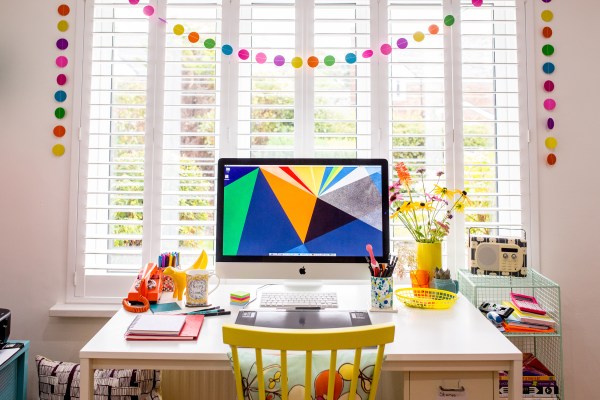 Computer with colorful desktop on desk with bunting behind