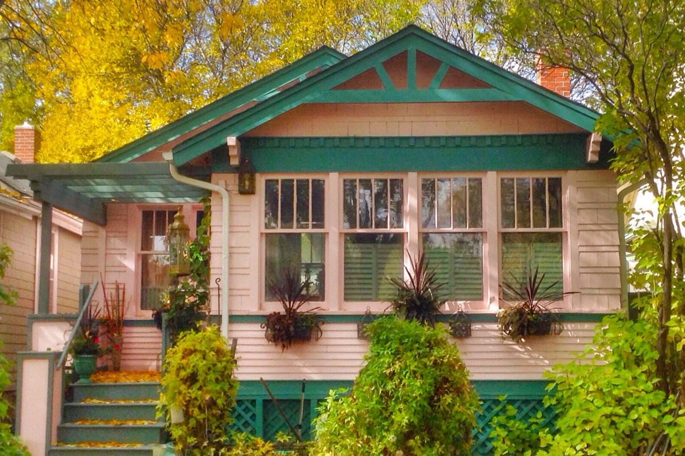 Pink wood-sided house with green trim against autumn foliage