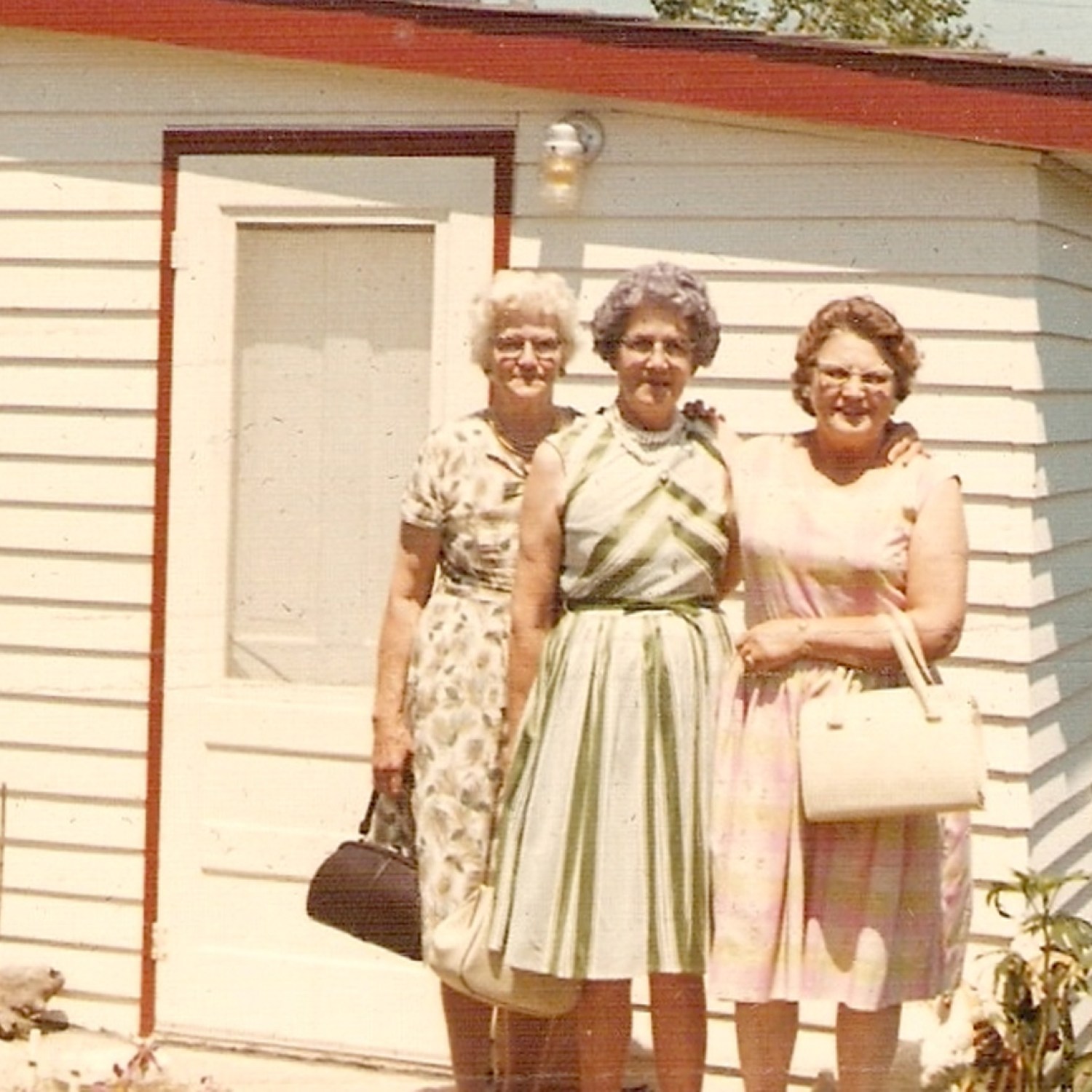 Three old ladies in front of a white building