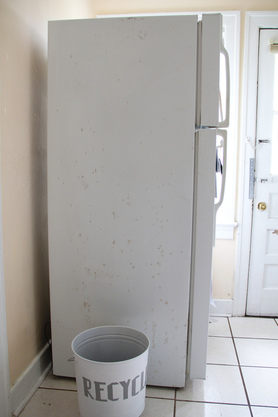 Side of an old white refrigerator in a kitchen