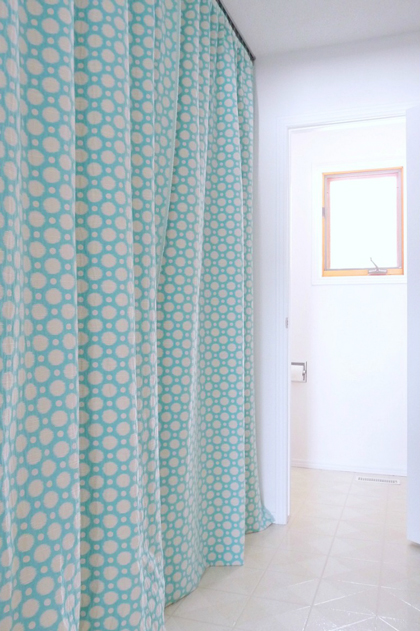 A blue green curtain hiding washer and dryer