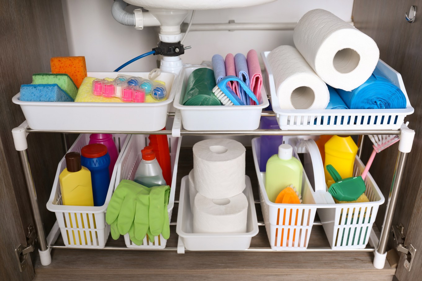 Open under sink cabinet with different cleaning supplies in kitchen