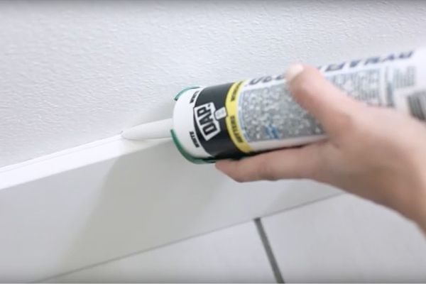 Woman applying caulk to a wall