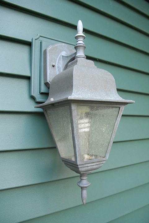 Green house siding with old silver porch light