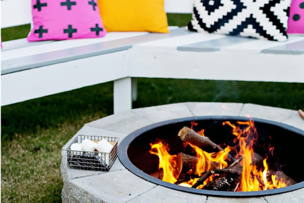 A firepit with a white bench with accent pillows