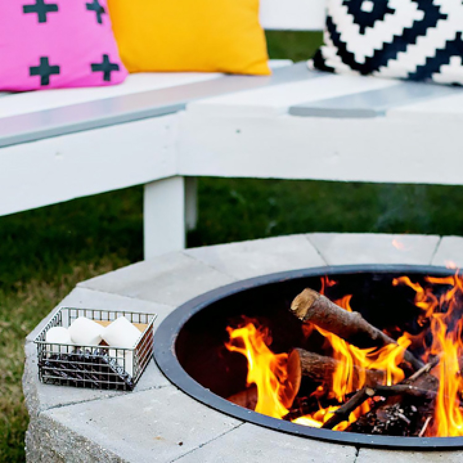 A firepit with a white bench with accent pillows