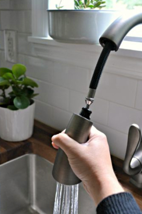 Hand holding kitchen faucet
