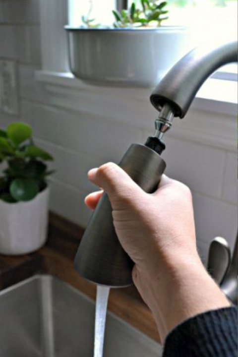 Hand holding kitchen faucet