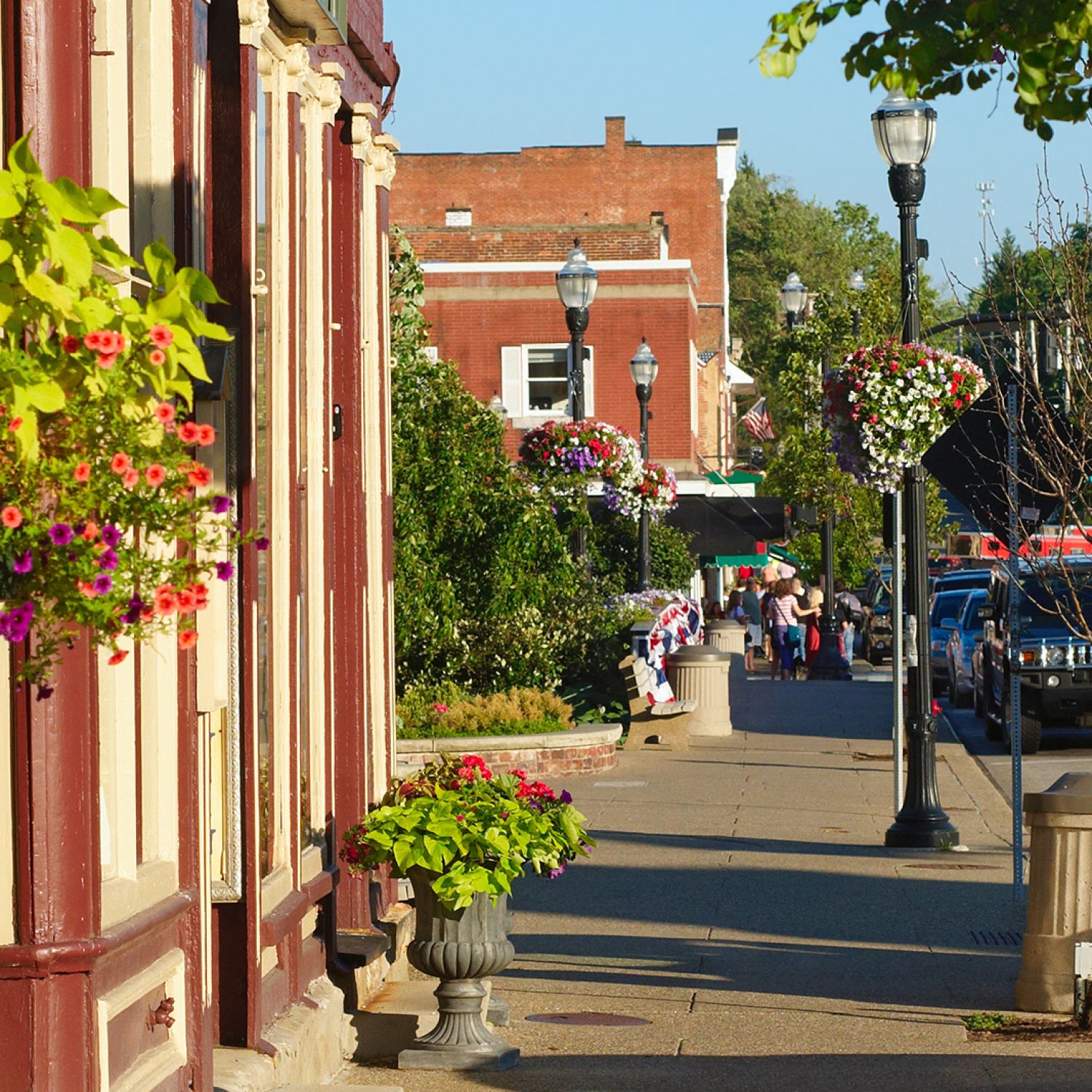 Bright sidewalk with store fronts and hanging flower baskets