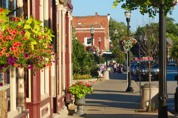 Bright sidewalk with store fronts and hanging flower baskets