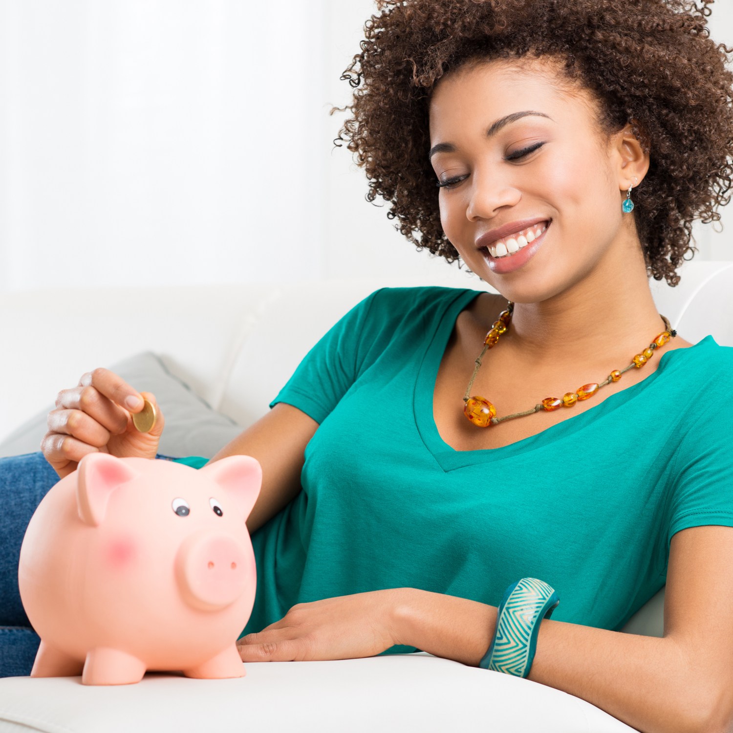 Woman sitting on a couch with a piggy bank
