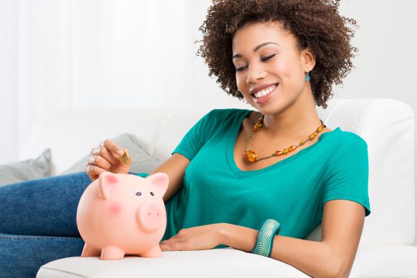 Woman sitting on a couch with a piggy bank