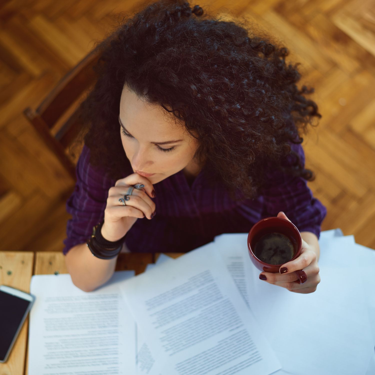 Overhead view of woman sitting at a wood desk with papers