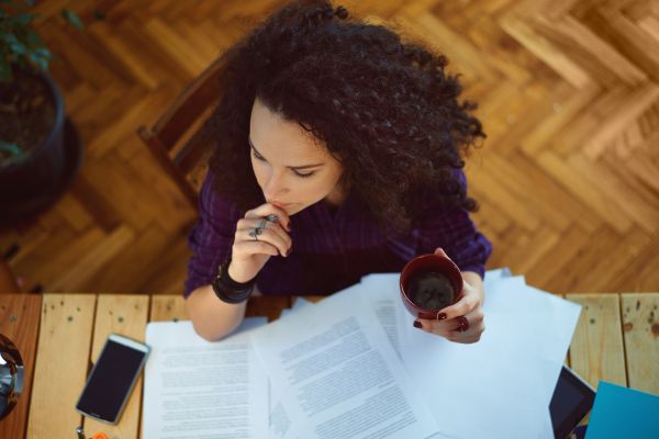 Overhead view of woman sitting at a wood desk with papers