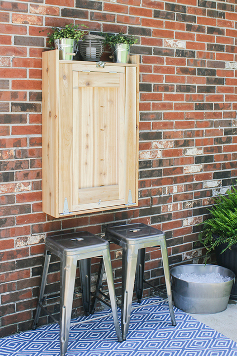 Closed wood cabinet on a brick wall with gray stools