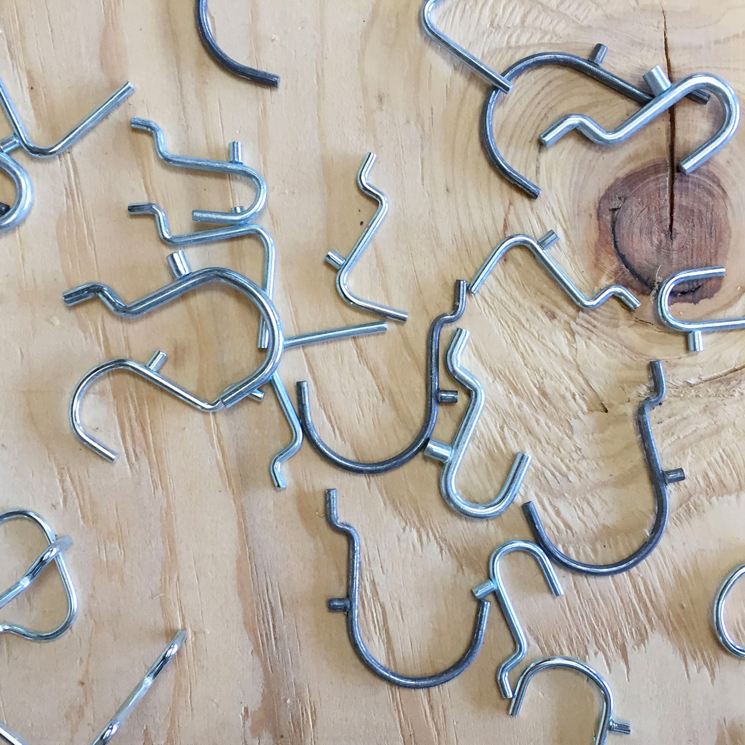 Several metal pegboard hooks on plywood