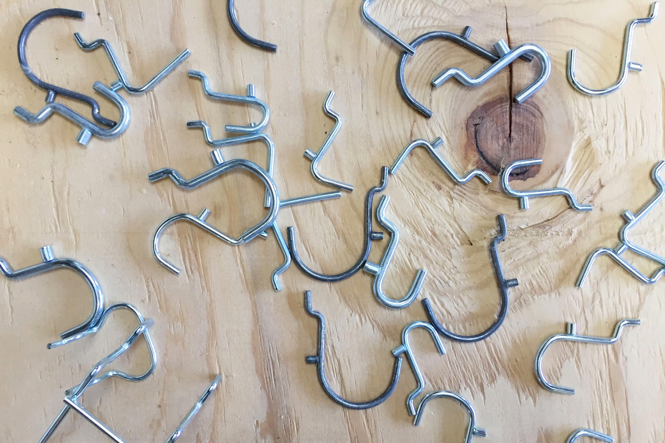 Several metal pegboard hooks on plywood