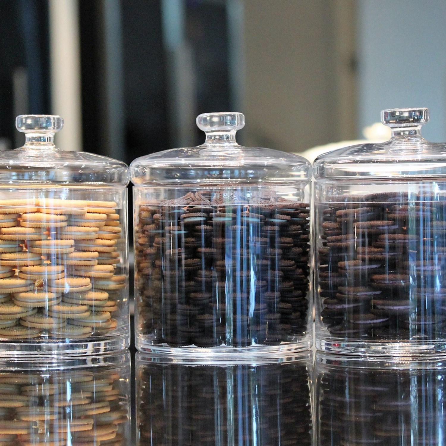 Three clear glass canisters filled with sandwich cookies