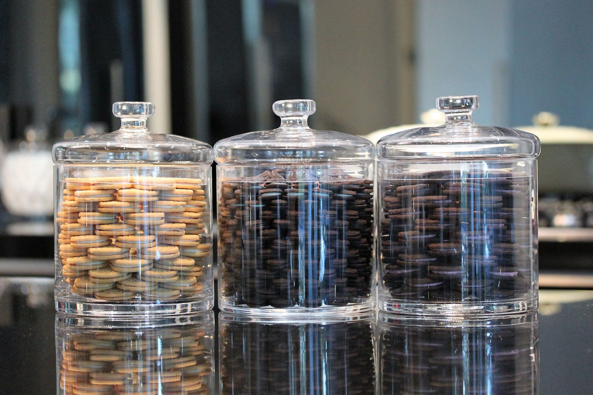 Three clear glass canisters filled with sandwich cookies