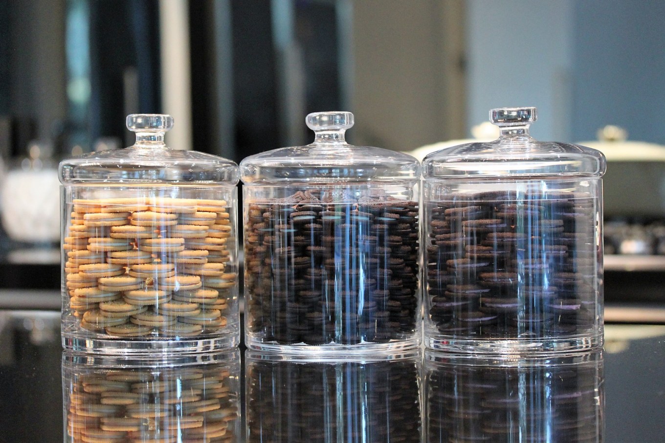 Three clear glass canisters filled with sandwich cookies