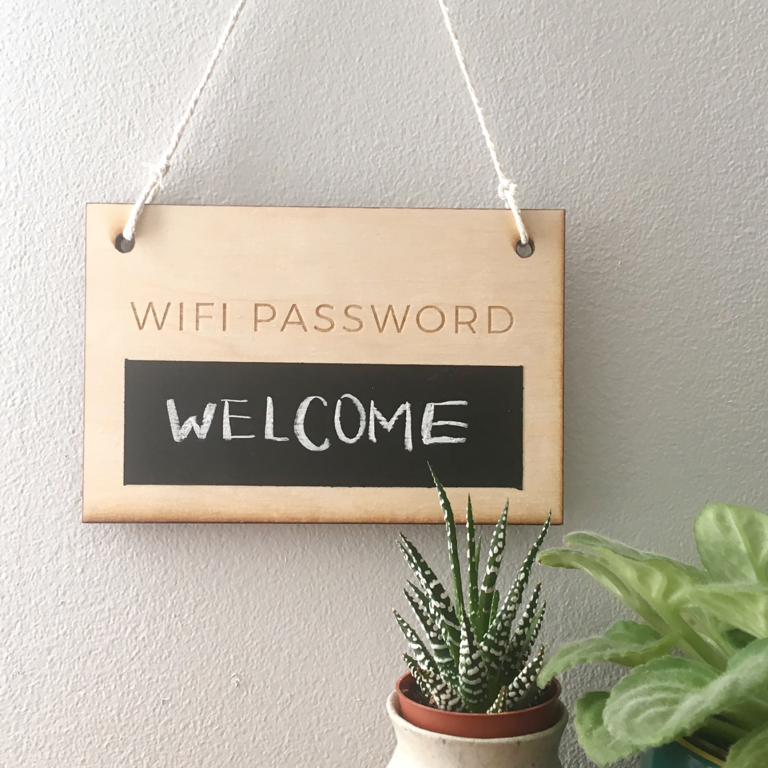 A wooden chalkboard Wi-Fi password sign with a succulent