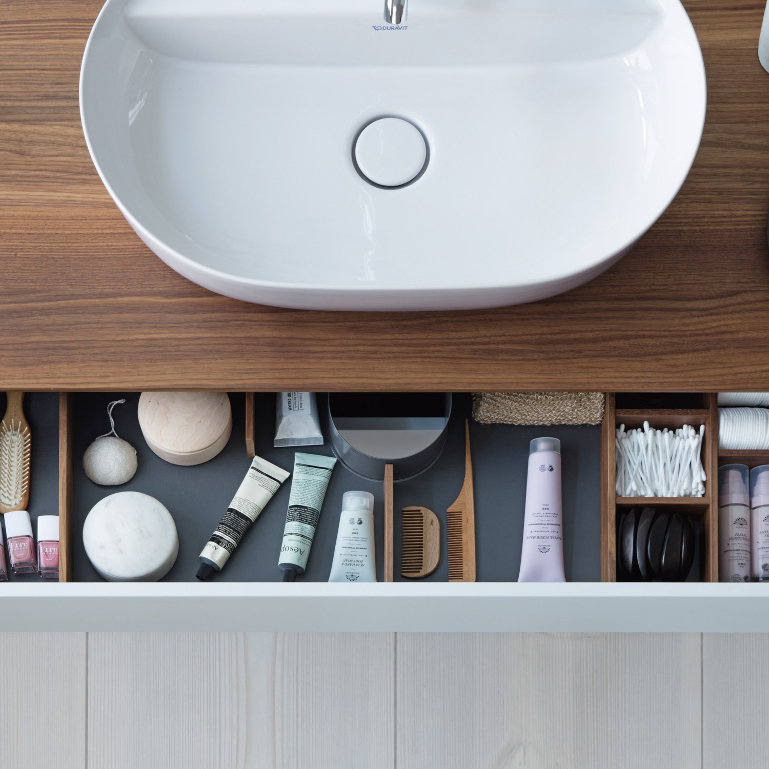 An overhead view of a bathroom sink and open drawer