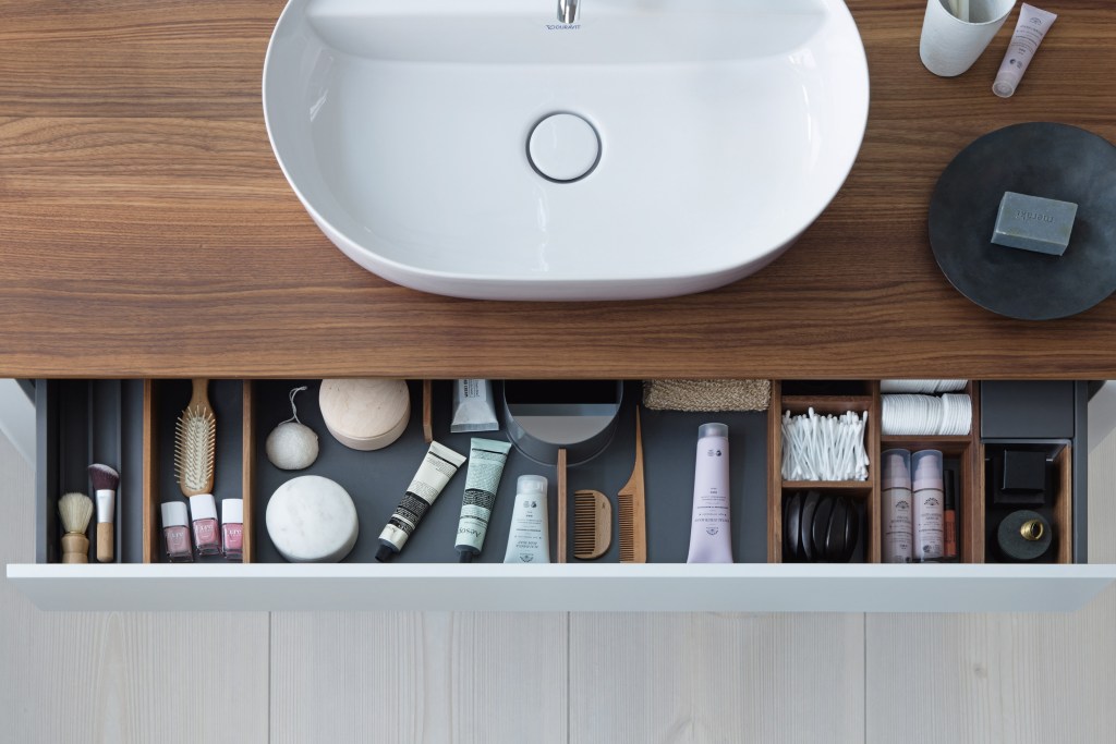 An overhead view of a bathroom sink and open drawer